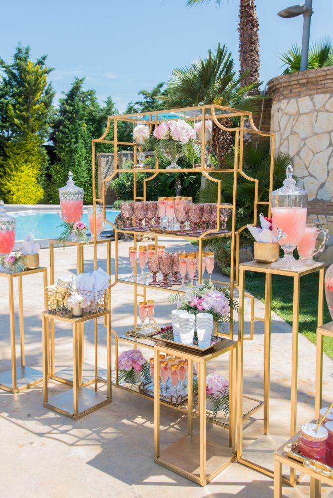 Gold wedding refreshment stand with pink lemonades for the guests.
