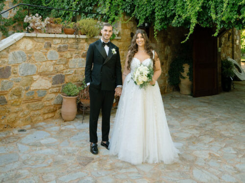 Bride and groom exchanging vows under floral arch at outdoor wedding